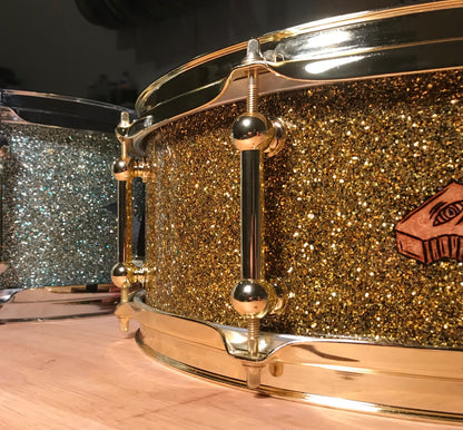 closeup view of two custom snare drums finished in gold sparkle and blue sparkle
