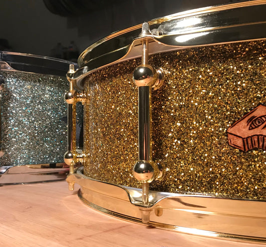 closeup view of two custom snare drums finished in gold sparkle and blue sparkle