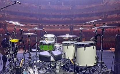 white drum set on stage with a custom green brownie snare drum